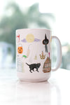 Hocus Pocus mug. The infamous spell book, the Sanderson Sisters' hairstyles, the cauldron, Old Burial Hill cemetery, Billy Butcherson's headstone, the vacuum, broom, and mop, the black flame candle, Dani's witch hat, Binx the black cat, the Sanderson house